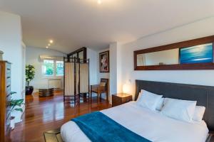 a bedroom with a large white bed and a wooden floor at Villa La Perla De Sonabia in Oriñón