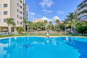 a large blue swimming pool in front of a building at Aptos Turísticos Playa Marinsa in Torre del Mar