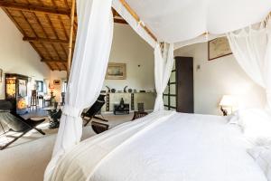 a bedroom with a large bed with white drapes at Le Palmier Exotique - Bazas in Bazas +13 photos