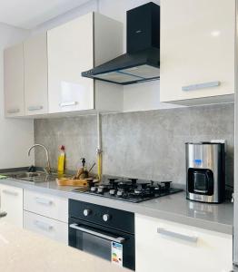 a kitchen with white cabinets and a black stove top oven at Studio Al Wahat in Douar el Hafey +5 photos