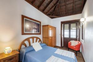 ein Schlafzimmer mit einem blauen Bett und einem Stuhl in der Unterkunft Casa El Café in Las Tricias
