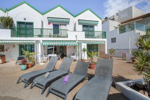 a row of chaise lounge chairs in front of a building at Casa Carmelo in Patalavaca