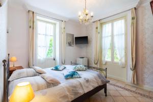 a bedroom with a bed with a chandelier and windows at Chambre D'hôtes Vignols in Vignols