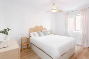 a white bedroom with a large bed and a window at Apartamento Bilua in Luanco