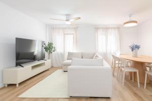 a white living room with a white couch and a tv at Apartamento Bilua in Luanco