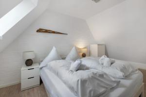 a white bedroom with a large bed with white sheets at Häuschen Seerobbe in Böhl