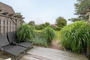 a wooden deck with two chairs and some tall grass at Häuschen Seerobbe in Böhl