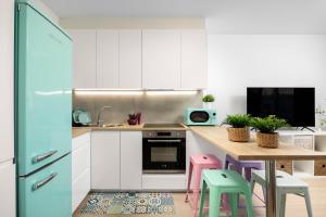 a kitchen with white cabinets and a table with stools at Capricho Torre del mar in Torre del Mar