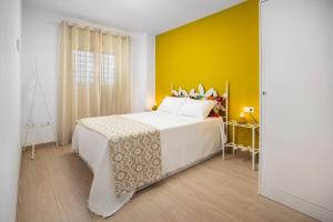 a bedroom with a large bed with a yellow wall at Capricho Torre del mar in Torre del Mar