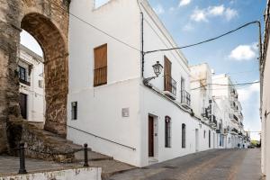 an alley with white buildings and an archway at Rosa in Vejer de la Frontera