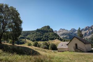 a house in a field with mountains in the background at Chalet Confortable 14 voyageurs in Urdos