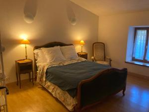 a bedroom with a bed with two lamps and two chairs at Chez Bonneau in Nantiat