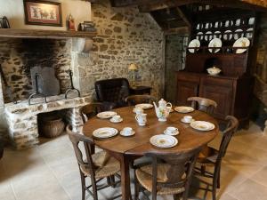 a dining room with a wooden table and a fireplace at Chez Bonneau in Nantiat