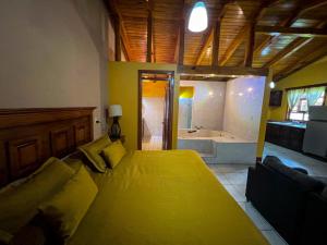 a bedroom with a large yellow bed and a bath tub at Cabañas Rosy in Mazamitla