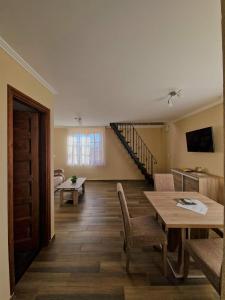 a living room with a table and chairs and a staircase at Szilvaliget Vendégház in Tolcsva