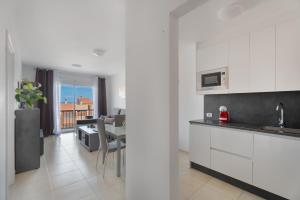 a kitchen with white cabinets and a living room at Apartamento Gabriela in Candelaria