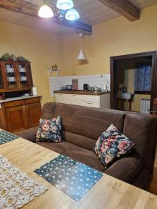 a living room with a brown couch and a kitchen at Chata pod Mogielicą - klimatyczny dom na wyłączność z ogrodem i widokiem na góry in Słopnice +38 photos