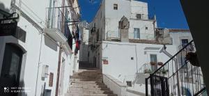 a narrow alley with white buildings and stairs at Mikiami Semplicemente Accogliente in Monte SantʼAngelo