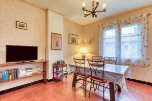 a dining room with a table and chairs and a television at La Coustouline in Lacoste