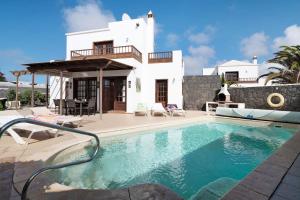 a villa with a swimming pool in front of a house at Serendipity in Playa Blanca