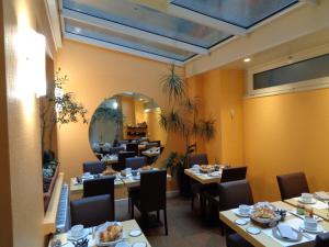 a dining room with tables and chairs and a mirror at Hotel de Montaulbain in Verdun-sur-Meuse