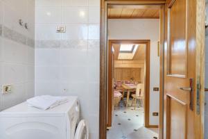 a bathroom with a washing machine and a dining room at Apartment Holzsuite in Fondo