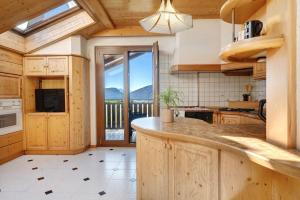 a kitchen with wooden cabinets and a large window at Apartment Holzsuite in Fondo