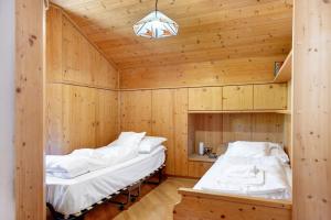 two beds in a room with wooden walls at Apartment Holzsuite in Fondo