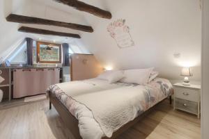 a bedroom with a bed with white sheets and a window at La Perle Rosée in Azerat
