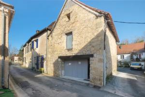 a stone building with a garage on a street at La Perle Rosée in Azerat