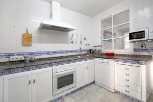a white kitchen with white cabinets and a sink at Espiritu Santo Velero 54 in Sanlúcar de Barrameda