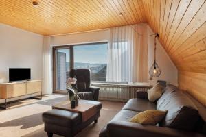 a living room with a couch and a chair and a large window at Maisonette auf 1000m mit Sauna in Schönwald