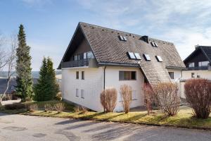 a white house with a black roof at Maisonette auf 1000m mit Sauna in Schönwald