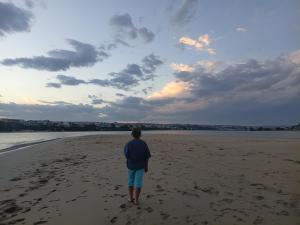 a person standing on a beach looking at the ocean at Kaalvoet Kaia in Stilbaai-Oos +4 photos