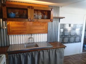 a kitchen with a sink and a wooden cabinet at Kaalvoet Kaia in Stilbaai-Oos