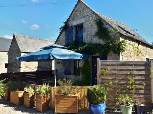 a house with an umbrella and some potted plants at Le Courtil De Bourrien in Languédias