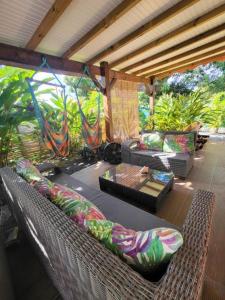 a wicker porch with a couch and a table at Gîte KAZ' A TYKA jacuzzi privatif in Saint-François