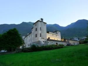a building in a field with mountains in the background at Il Pellegrino in Issogne