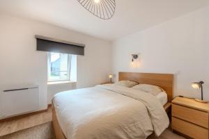 a white bedroom with a large bed and a window at Au Coeur De Plouguerneau in Plouguerneau