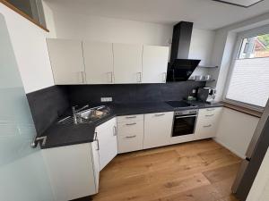 a small kitchen with white cabinets and a sink at Moderne Ferienwohnung Bodensee in Sigmarszell