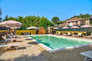 a swimming pool with tables and umbrellas and chairs at Clematis in Cisterna dʼAsti