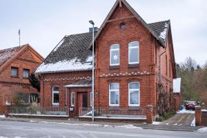 a red brick house with white windows on a street at Ferienwohnung Löwenstein in Hoya