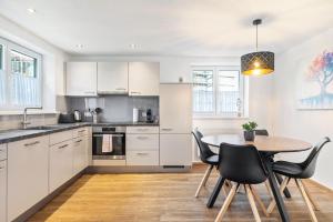 a kitchen with white cabinets and a table and chairs at Apartments Winder 2 in Lustenau