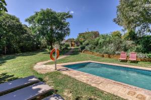 a swimming pool in a yard with two pink chairs at Mas la Ginesta in Borrassá
