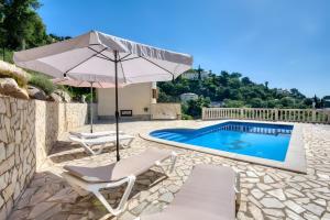 a swimming pool with an umbrella and two chairs and a swimming pool at Villa Speranza by Easy Brava in Calonge