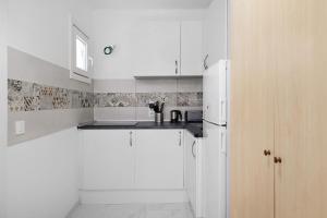 a kitchen with white cabinets and a white refrigerator at Kays studio in Puerto del Carmen +3 photos
