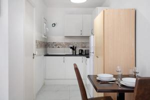a kitchen with white cabinets and a table with a dining room at Kays studio in Puerto del Carmen