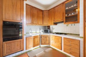 a kitchen with wooden cabinets and a stove top oven at Home Charlene parking e patio in Albenga +16 photos