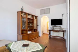 a living room with a television and a table with a desk at Home Charlene parking e patio in Albenga