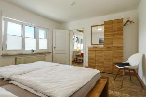 a bedroom with a large white bed and a chair at Ferienwohnung Eberle in Eriskirch